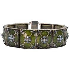 A distinct vintage piece, restored to its original vibrancy consisting of 10 moss green enamel base metal tiles linked to form this 7-1/2 inch bracelet. Each tile link is artfully decorated with silver-tone scroll work accented with complimenting White Sapphire and Black Onyx stone enhancements. Measuring 3/4 inches wide with brilliant color, this bracelet is finished with a modern Sterling Silver decorative filigree clasp. In gift box. Luxury Silver Enamel Bracelets, Antique Enamel Bracelets For Formal Occasions, Antique Enamel Bracelet For Formal Occasions, Vintage Enamel Jewelry With Rectangular Shape, Elegant Silver Enamel Bracelets, Vintage Rectangular Enamel Jewelry, Art Deco Green Bracelets For Formal Occasions, Art Deco Green Bracelet For Formal Occasions, Green Metal Bracelets For Formal Occasions