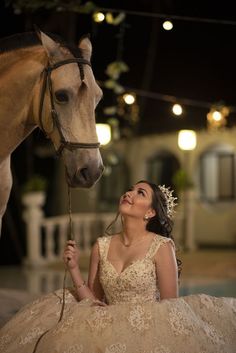 a woman in a wedding dress sitting next to a horse with lights on it's head