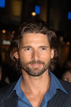 a man with long hair and beard wearing a blue shirt is looking at the camera