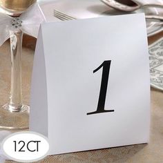 a white table number sitting on top of a table next to a wine glass and silverware