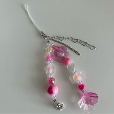 a pink and white beaded necklace on a silver chain with a butterfly charm hanging from it