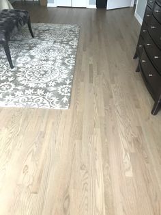 a living room with hardwood floors and white rugs on the floor next to a dresser