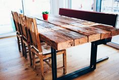 a wooden table with four chairs and a potted plant sitting on top of it