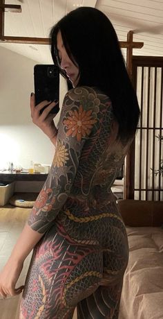 a woman with tattoos on her body taking a selfie in front of a mirror