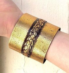 "Gold emboss leather cuff, an eye catcher bracelet with antique gold finish. Artisanal leather 3\" wide cuff with a braid stitch in the middle. Closure with two brass snaps. 7.5\" long when closed." Artisan Gold Bracelets For Festival, Artisan Gold Bracelet For Festivals, Gold Leather Bracelets As Gift, Gold Leather Bracelet For Gift, Gold Leather Bracelet As Gift, Unique Engraved Gold Cuff Bracelet, Handmade Gold Cuff Bracelet For Festival, Brown Metal Bracelets For Festival, Unique Handmade Gold Leather Bracelet