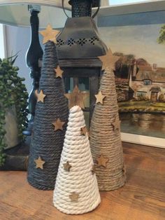 three small christmas trees are sitting on a table next to a lantern and some other decorations