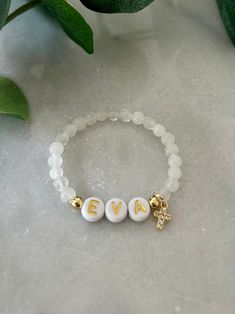 - The sweetest baby girl cross bracelet. Soft and delicate with dainty cross charm and personalized with name. Perfect goddaughter gift for baptism. Baby name bracelet is beaded on high quality stretch cord and secured.  - 4mm 18k gold filled accent beads   4.5mm gemstone beads ( white jade, rose quartz )   8mm cubic zirconia gold cross ‼️Young children MUST be supervised at all times while wearing jewelry. Contains small parts that could be a potential choking hazard. Jewelry should always be r Baby Beaded Bracelet, Personalized White Cross Jewelry, Personalized Cross Jewelry For Confirmation, White Cross Jewelry For Personalized Gift, White Cross-shaped Jewelry For Personalized Gift, Customizable White Rosary Bracelet As A Gift, Customizable White Rosary Bracelet As Gift, Customizable White Rosary Bracelet Gift, Adjustable Cross Bracelets For Baptism