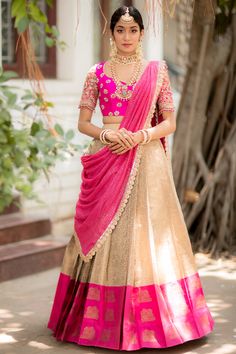 a woman in a pink and beige lehenga