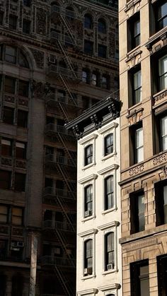 an old building is next to a newer one in the city with fire escapes on it