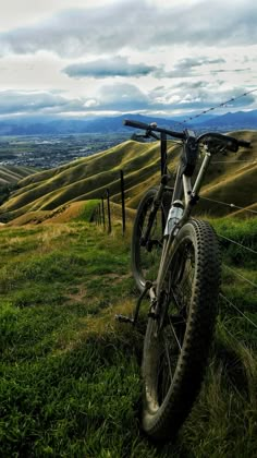 a mountain bike parked on top of a lush green hillside