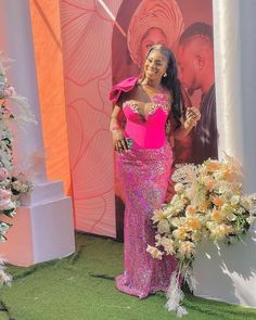 a woman in a pink dress standing next to a flower display with flowers on it