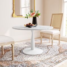 a white table with two chairs and a vase filled with flowers on top of it