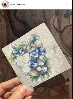 someone holding up a card with an image of flowers and leaves on the inside of it