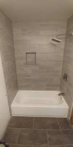 a white bath tub sitting inside of a bathroom next to a shower head and hand rail