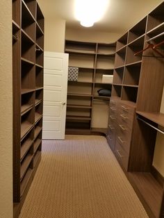 an empty walk in closet with lots of shelves and drawers on either side of the door