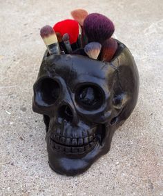 a skull with makeup brushes in it on the ground