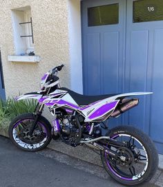 a dirt bike parked in front of a blue garage door on the side of a street