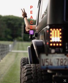 a person is waving from the back of a jeep with peace written on its side