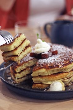 a stack of pancakes on a plate with butter and syrup being drizzled over them