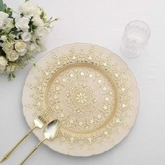 a white and gold plate sitting on top of a table next to a vase with flowers