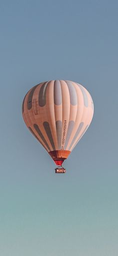 a hot air balloon flying in the sky with a clear blue sky behind it on a sunny day