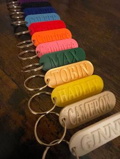 a row of personalized key chains with name tags attached to them on a wooden table