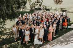 a large group of people standing together in front of a tree and fenced area