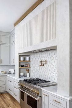 a kitchen with white cabinets and stainless steel stove top oven in the center of the room