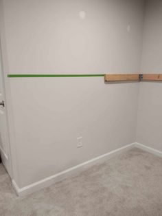 an empty room with white walls and green lines painted on the wall, along with carpeted flooring