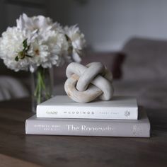 a couple of books sitting on top of a table next to a vase with flowers