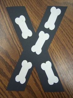 the letter k is made out of black paper with white dog bone cutouts on it