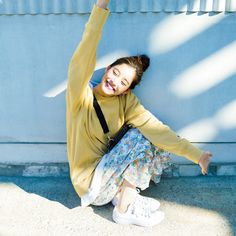 a woman sitting on the ground with her arms in the air, smiling and stretching