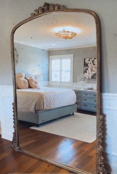 a bedroom with a large mirror on the wall and hardwood flooring in front of it