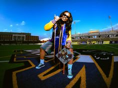 a girl is posing with her skateboard in front of the football field and stadium