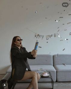 a woman sitting on top of a couch with confetti falling from her hands