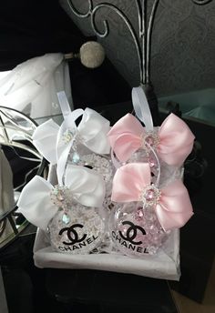 two chanel perfume bottles with pink bows and crystal stones in them sitting on a table