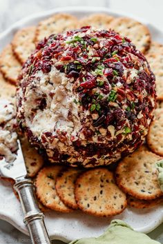 a cheese ball with cranberry sauce and crackers on a white platter