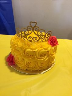 a cake with yellow frosting and red flowers on top, sitting on a table