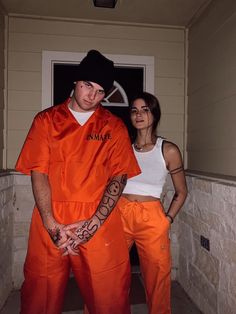 two people in orange prison uniforms standing next to each other with tattoos on their arms