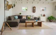 a living room filled with furniture and lots of plants on top of the floor next to a white brick wall