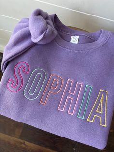 This cozy pullover sweatshirt is cotton/poly blend is embroidered with your little one's name across the front of the chest in the prettiest colors! Color shown is lavender which is not listed on the chart but is available in the drop down menu.  Please wash on cold and dry on low. If you are wanting a different design, more wording, or a different clothing style, please send me a message so we can discuss the details. Please leave the thread color you would like in the personalization box. Cute Crew Neck Sweatshirt For School, Long Sleeve Fleece Top With Letter Embroidery, Fleece Top With Letter Embroidery And Long Sleeves, Purple Letter Print Sweater For Fall, Cute Purple Cotton Hoodie, Fleece Crew Neck Tops For School, Multicolor Fleece Crew Neck Sweatshirt, Purple Crew Sweatshirt For Winter, Purple Crew Neck Sweatshirt For Winter