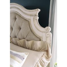 the headboard and foot board of an antique style bed with ruffled linens