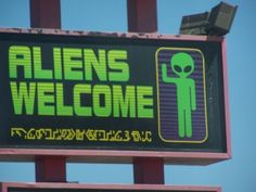 a sign that says aliens welcome with an alien on it