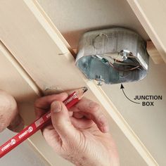 a man is working on an electrical box with a pencil in his hand and the junction box labeled