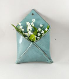 a blue vase filled with white flowers sitting on top of a table next to a pillow