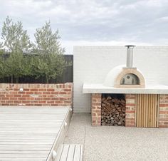 an outdoor pizza oven with wood stacked in it