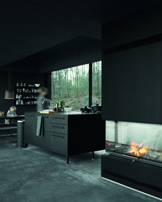 a woman sitting in front of a fire place next to a counter top with an oven on it