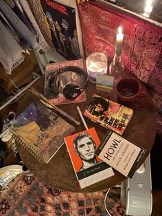 a table topped with books and candles next to a wall covered in posters on it