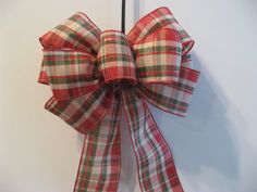 a red and green plaid bow hanging on a door