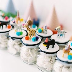 there are many small glass jars filled with candies and animals on top of them